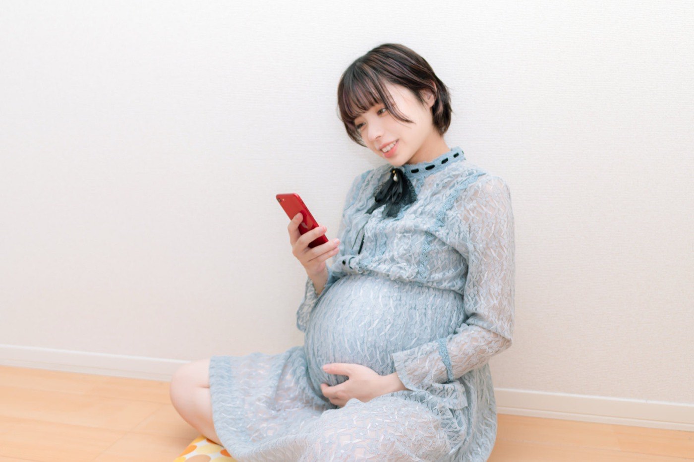 スマホを見ながら、おなかに手をそえる妊婦さん